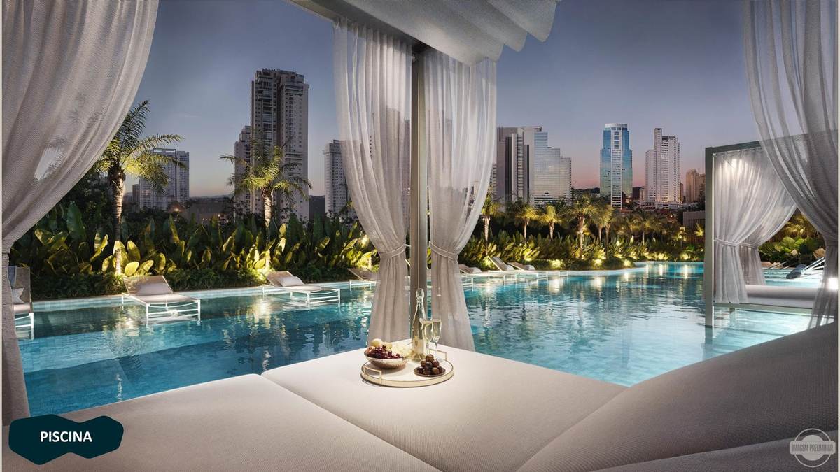 Piscina ao entardecer com camas balinesas e vista para as torres de Alphaville