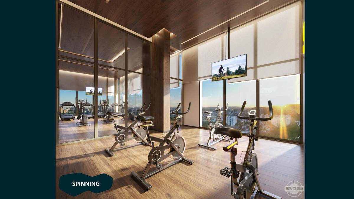 Sala de spinning com bikes e vista do pôr do sol sobre Alphaville